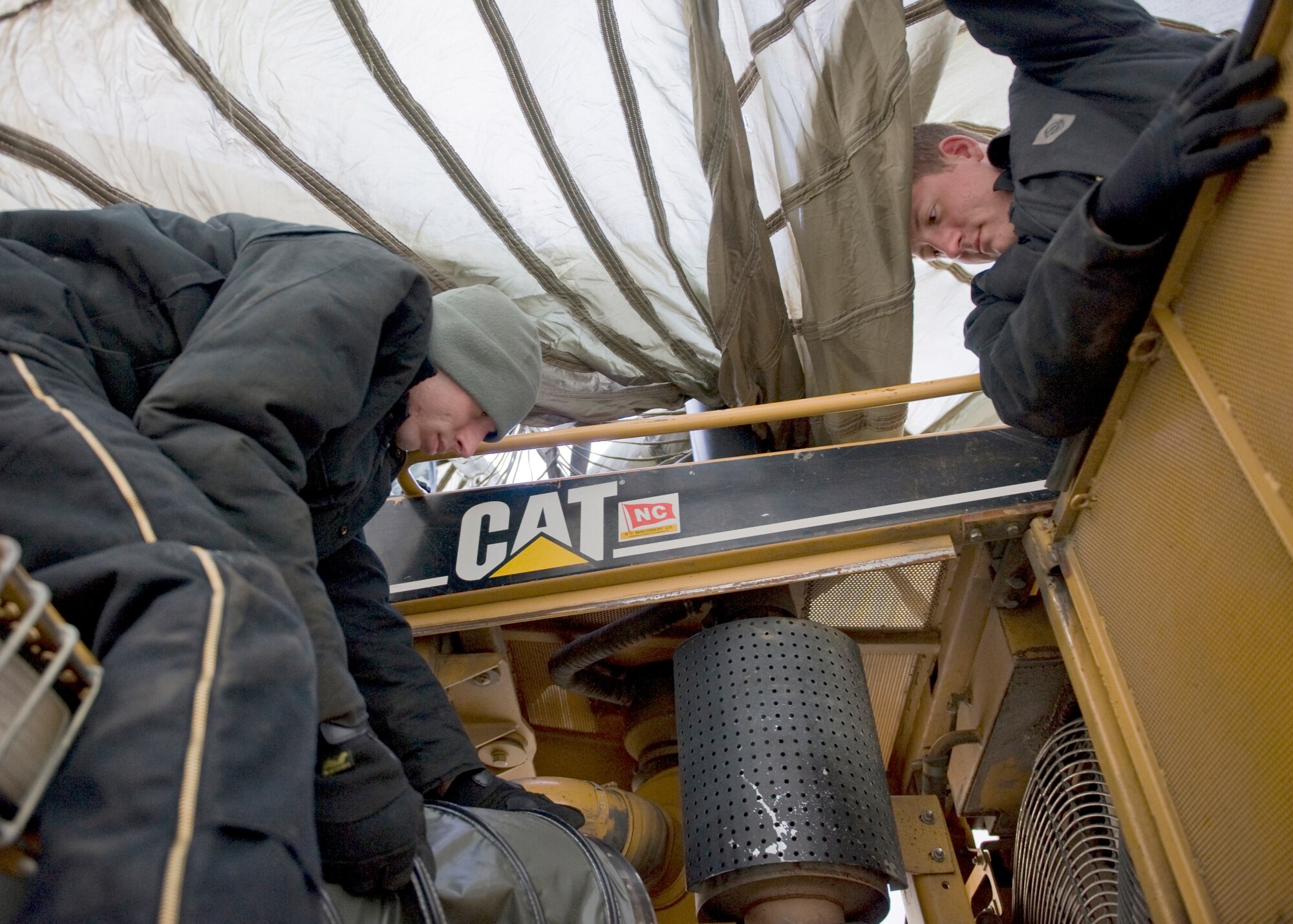 Airman 1st Class Patrick Elkins and Senior Airman Sean Goddard, 354th Logistics Readiness Squadron vehicle journeymen, work to repair a frozen bulldozer Nov. 19, 2013, Eielson Air Force Base, Alaska. Jump starting a frozen battery without first thawing it can cause it to explode. (U.S. Air Force photo by Senior Airman Ashley Nicole Taylor/Released)