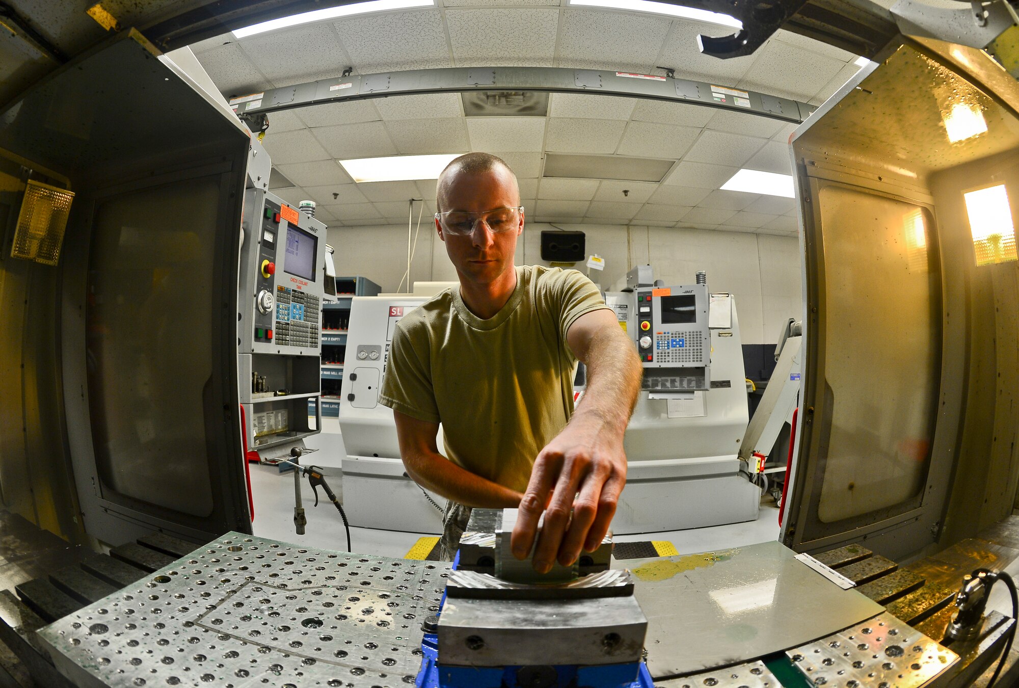 Staff Sgt. Michael Johnson, 6th Maintenance Squadron aircraft metals technology craftsman, readies a computer numerical control machine at MacDill Air Force Base, Fla., Nov. 5, 2013. The Computer numerical control takes coded alphanumeric data and precisely manufactures parts through controlled depth of cuts. (U.S. Air Force photo by Staff Sgt. Brandon Shapiro/Released)