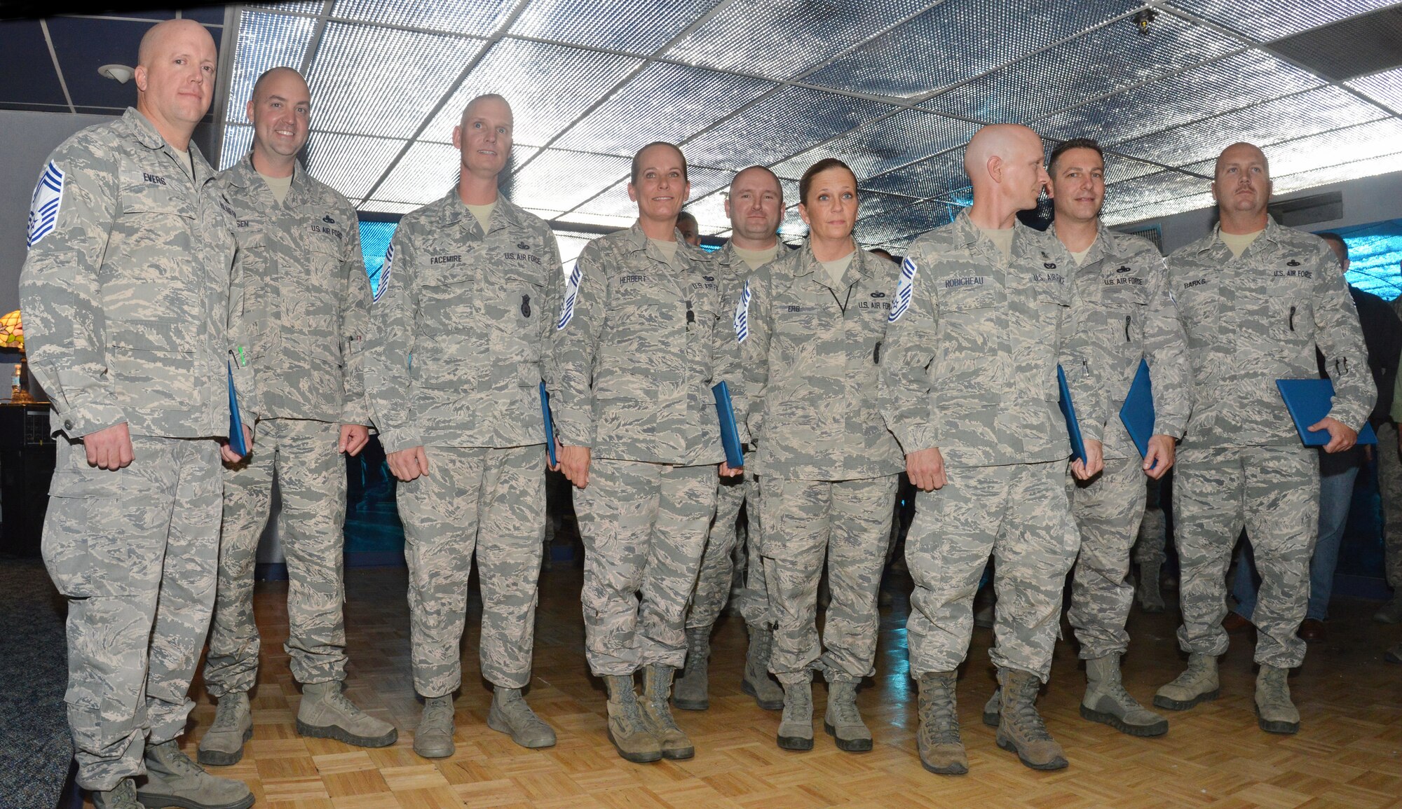 The nine Team Kirtland chief master sergeant selects pose a the induction ceremony.  From left to right: Eric Evers, 58th Aircraft Maintenance Squadron; Joshua Hansen, 58th AMXS; John Facemire, 377th Security Forces Squadron; Susanne Herbert, 58th Maintenance Squadron; Patrick McFarlin, 58th Special Operations Wing;  Melissa Erb, Defense Threat Reduction Agency; Michael Robicheau; 58th Aircraft Maintenance Squadron; Vincent Stephenson, Air Force Inspection Agency; and Christopher Barks, 898th Munitions Squadron