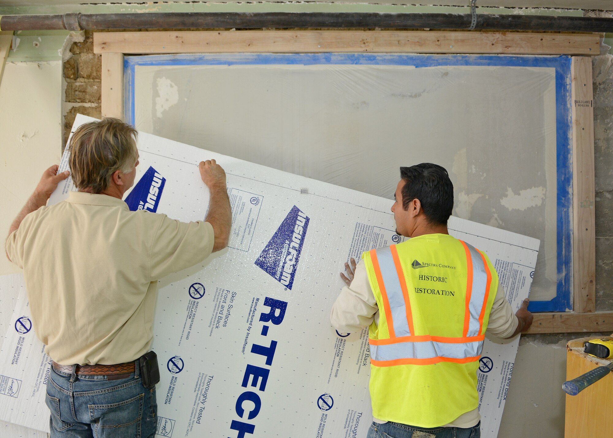 Tom Bilisoly (left), Spectra Company supervisor and senior artisan, and Damien Mortino, Spectra Company craftsman and artisan, prepare to encase and protect the historic Muroc Manor signature wall from any debris during the wall’s extraction process. The signature wall potentially holds hundreds of signatures dating from the early 1940s to the 1960s. Since the wall was previously painted over, the team had to bring in an infrared camera to further evaluate the structure in order to carefully remove the wall. (U.S. Air Force photo by Jet Fabara)