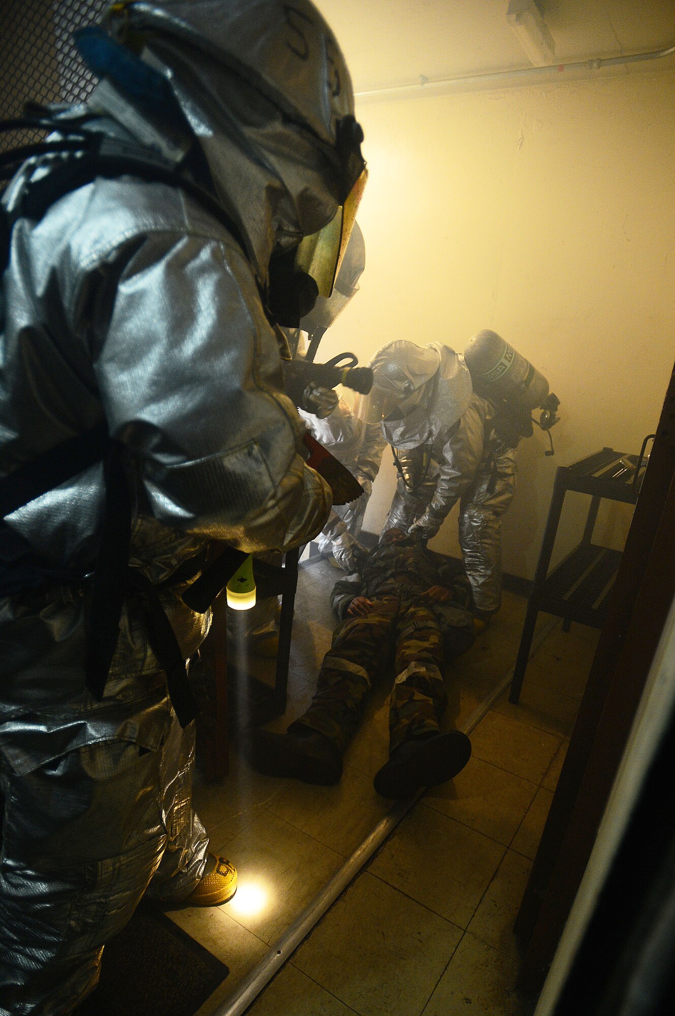 Firefighters of the 48th Civil Engineer Squadron drag a mock victim away from a simulated building fire during a Phase II exercise at building 1240 on Royal Air Force Lakenheath, England, Nov. 20, 2013. One aspect of the Phase II is testing the response capabilities of Airmen through various scenarios to ensure mission readiness.  (U.S. Air Force photo by Senior Airman Tiffany M. Grigg/Released)