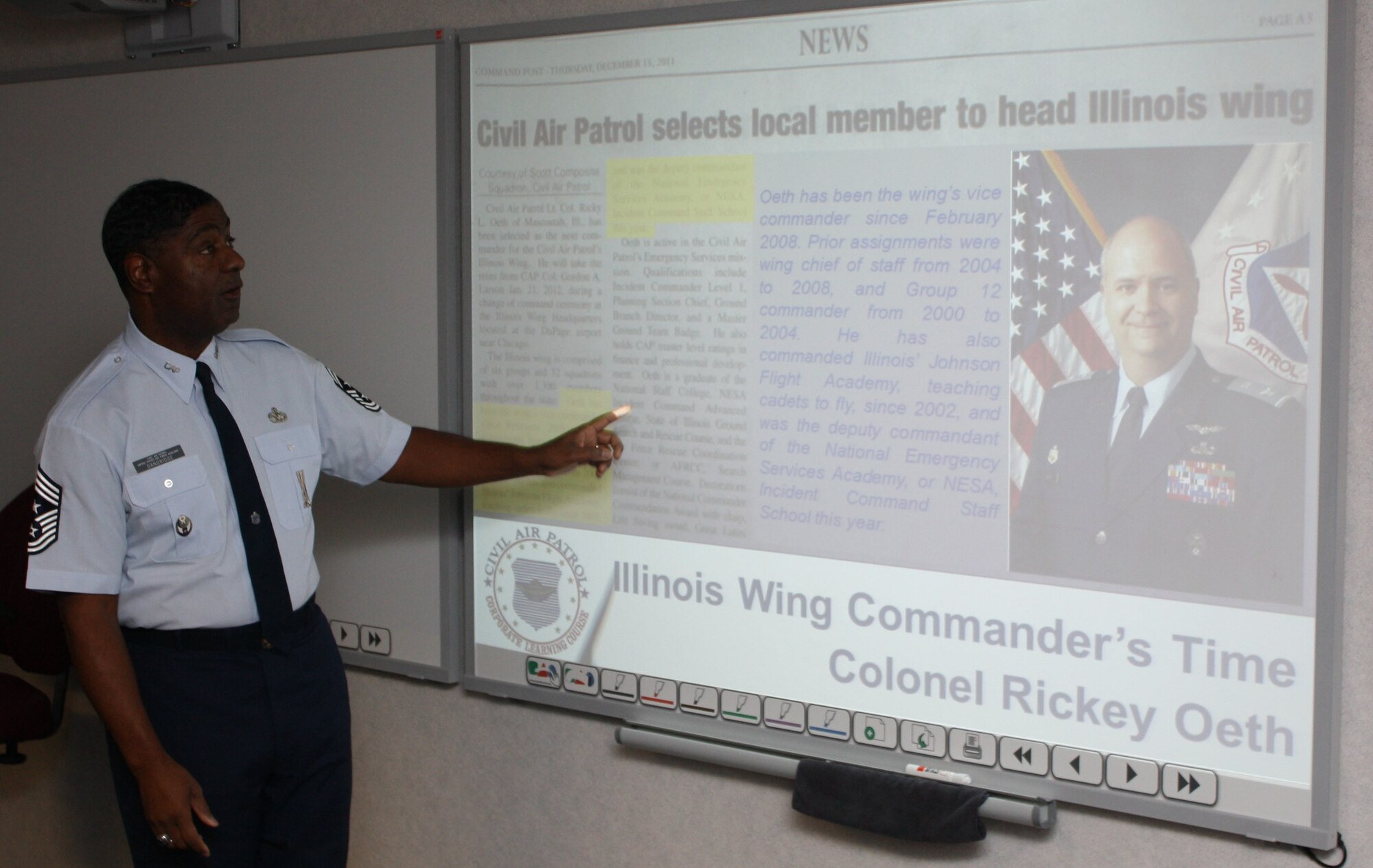 Retired Air Force Command Chief Master Sgt. Robert Dandridge, Illinois wing’s Enlisted Advisor to the Commander, points out some of the key accomplishments of Col. Rickey Oeth as he prepares to introduce the wing commander to students in the Corporate Learning Course. (CAP Photo by Capt. Greg Hoffeditz)