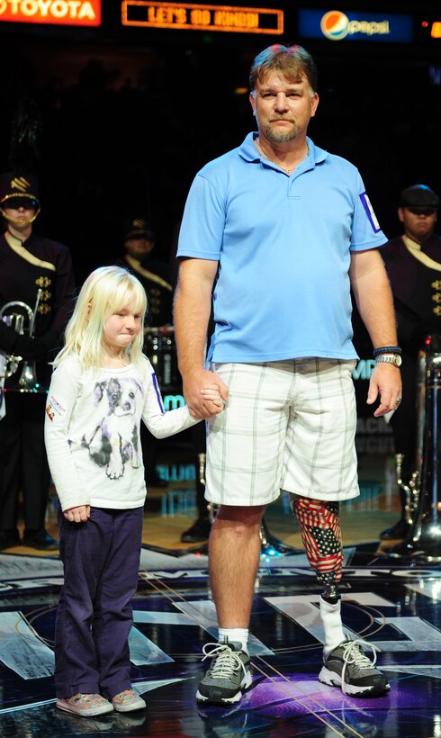 Christopher Paulsen is honored with his daughter Abigail during a military appreciation night Nov. 13, 2013, at the Sleep Train Arena in Sacramento Calif. Chris lost the lower portion of his left leg while serving as an aviation ordinance man aboard the USS Constellation. (U.S. Air Force photo by Airman 1st Class Bobby Cummings/Released)