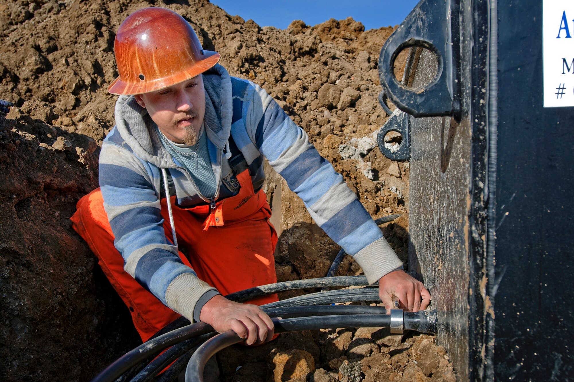 Cristian Coffey, a geothermal contractor, installs well supply and return lines to a vault at Grissom Air Reserve Base, Ind., Oct. 22, 2013. Four energy-saving vaults are being installed, each connecting seven 300-foot wells used to supply heating and cooling to Bldg. 671.