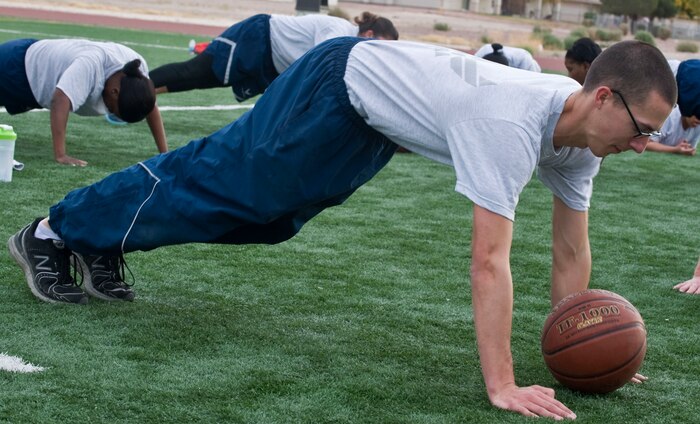 U.S. Air Force Airman 1st Class James Vrtis, 99th Communications Squadron air field systems journeyman, performs basketball pushups during the Warrior Trained Fitness workout on the field behind the Warrior Fitness Center Nov. 19, 2013, at Nellis Air Force Base, Nev. The second part of the event consisted of five stations for participates to rotate through. In this particular station participants would have one hand on the basketball while performing pushups and alternate hands on each push up. (U.S. Air Force photo by Senior Airman Matthew Lancaster)