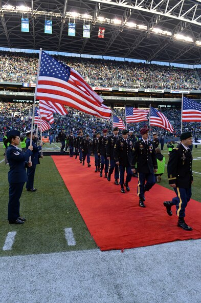 Service members hold American flags as 15 Army Purple Heart medal recipients leave the “Salute to Service" halftime ceremony at Safeco Field, Jan. 17, 2013 in Seattle, Wash. The Purple Heart medals were awarded to Army Soldiers for wounds received in combat. (U.S. Air Force photo/Staff Sgt. Jason Truskowski)