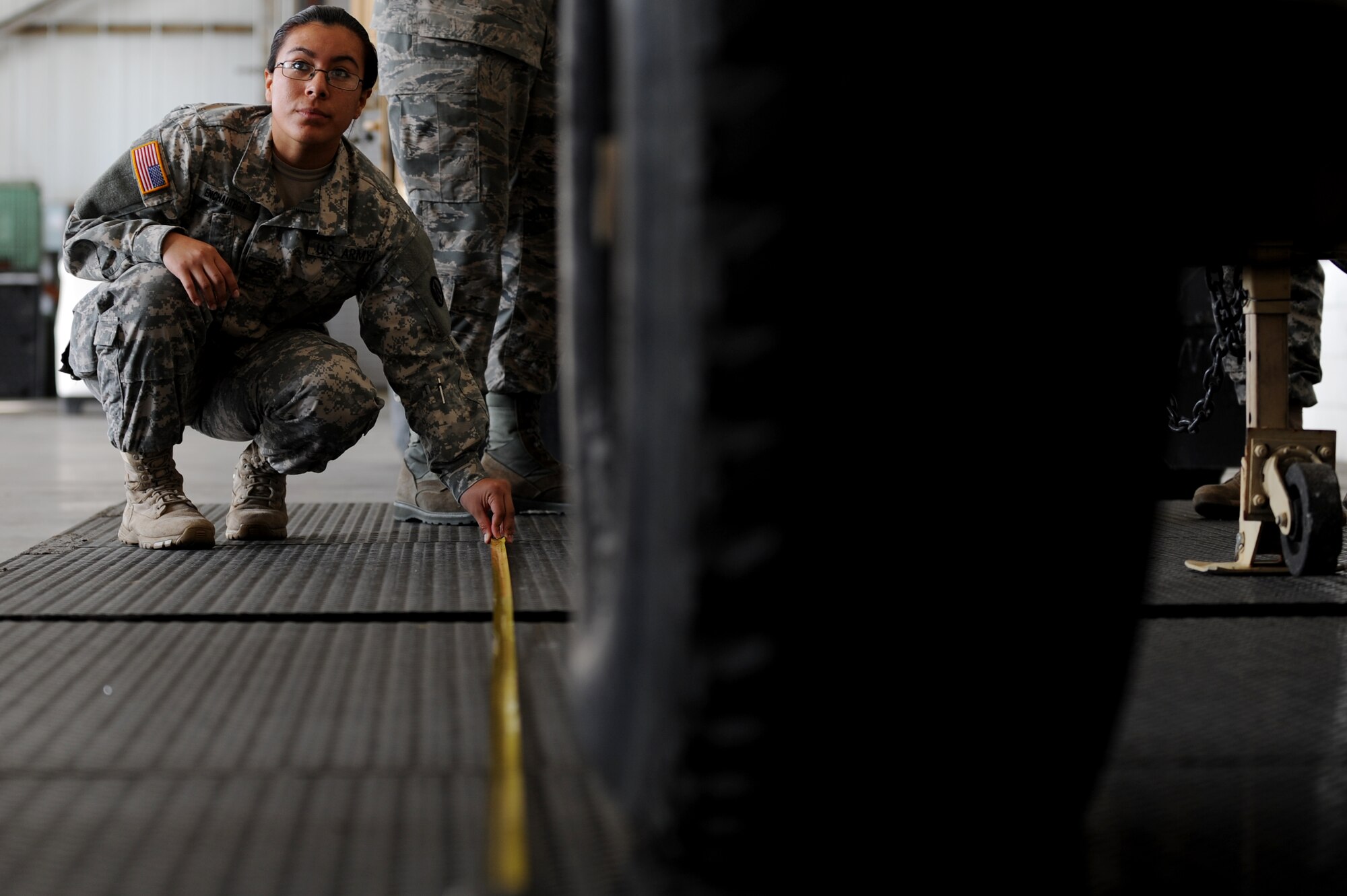 U.S. Army Pfc. Jackie Enchautegui, from the 689th Rapid Port Opening Element, measures a Humvee parked inside the Small Air Terminal at Langley Air Force Base, Va., during a joint training exercise, Nov. 19, 2013. Soldiers measured and weighed the vehicle to determine the precise balance point and position it would need to occupy aboard an aircraft. (U.S. Air Force photo by Staff Sgt. Jarad A. Denton/Released)