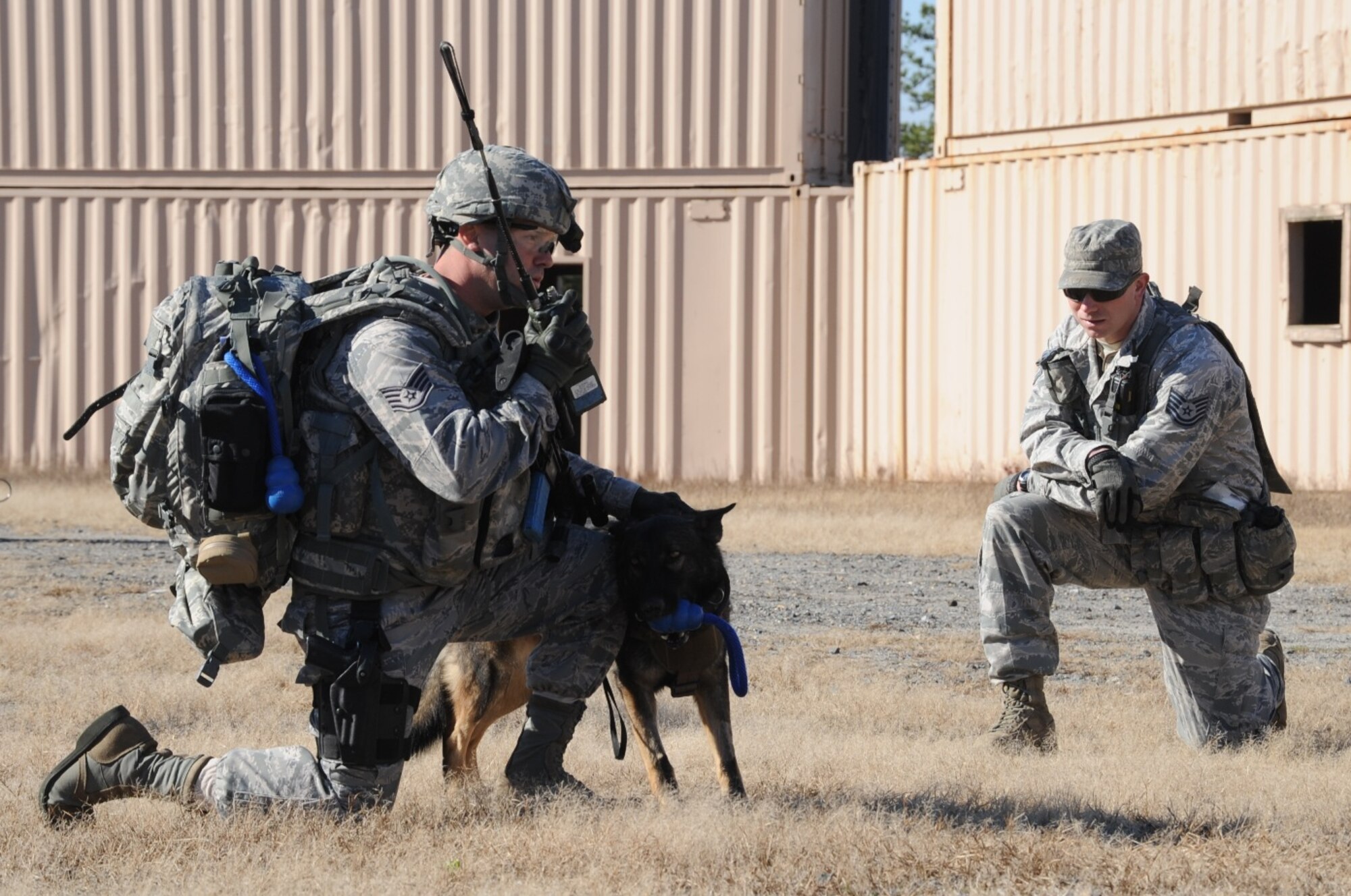 Staff Sgt. Brandon Serena, military working dog handler from Patrick Air Force Base, Fla., calls in a 9-Line improvised explosive device report with Rocky, a MWD, at his side while Tech. Sgt. Matthew Lee, 421st Combat Training Squadron MWD cadre, observes the exercise during the MWD Base Security Operations Course Nov. 10, 2013, at Joint Base McGuire-Dix-Lakehurst, N.J.  (U.S. Air Force photo by Staff Sgt. Nathaniel Bevier/Released)