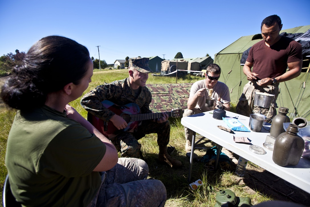 Sgt. Greg Wubben, a civil affairs non-commissioned officer with 1st Civil Affairs Group, I Marine Expeditionary Force, from Ridgefield, Wash., plays guitar and talks with members of the New Zealand Defence Force in the field during exercise Southern Katipo 2013 aboard Timaru, New Zealand, Nov. 16. SK13 strengthens military to military relationships and cooperation with partner nations and the New Zealand Defence Force. 