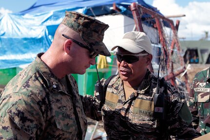 Philippines Navy Capt. Vincent Trinidad, right, and U.S. Marine Lt. Col. Travis T. Gaines speak Nov. 18, 2013, at Tacloban, Republic of the Philippines. At the request of the Government of the Philippines, U.S. military members have been providing support to the Armed Forces of the Philippines as part of Operation Damayan following Typhoon Haiyan.