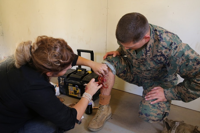 MARINE CORPS BASE CAMP PENDLETON, Calif., -- Kasey Erokhin, co-owner of KBZ FX special effects medical training support system, applies special effects moulage to Capt. Shawn Ridings, assistant operations officer, Tango Battery, 5th Battalion, 11th Marine Regiment, and a native of Bonney Lake, Wash., to simulate an open fracture casualty during a training exercise at the Mobile Immersion Trainer here, Nov. 14, 2013. The MIT is similar to the Infantry Immersion Trainer and trains Marines to operate under stressful conditions. Throughout the morning, the battery simulated operating out of a base and posted security while mock insurgents attempted to breach the area and formed riots. The artillerymen later conducted a logistics patrol and recovered a broken vehicle, countered an improvised explosive device and repelled enemy role-players during an ambush. The battery is slated to continue predeployment training before deploying to Afghanistan this winter.
