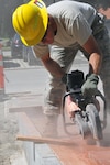 Air Force Master Sgt. Jesse Johnson, with the Wyoming Air National Guard's 153rd Civil Engineer Squadron, cuts pavers for a new walkway at the NATO School in Oberammergau, Germany, Aug. 20, 2012.