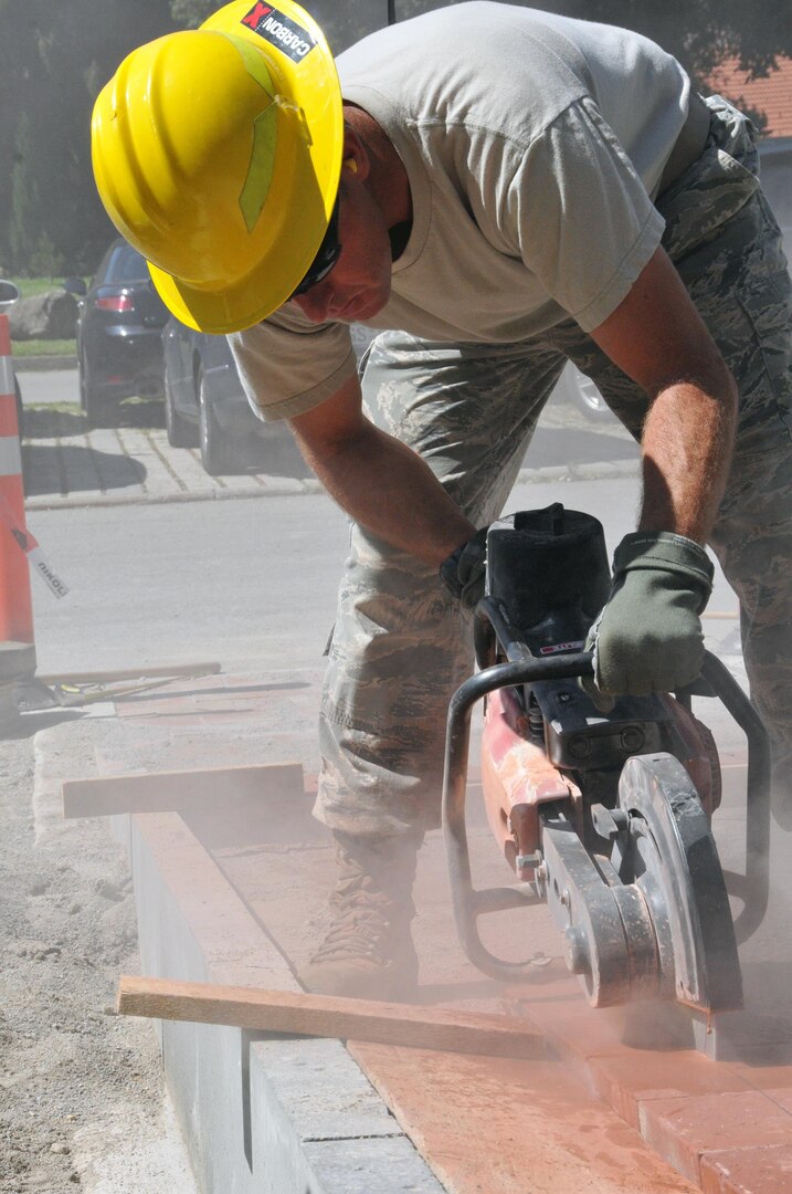 Air Force Master Sgt. Jesse Johnson, with the Wyoming Air National Guard's 153rd Civil Engineer Squadron, cuts pavers for a new walkway at the NATO School in Oberammergau, Germany, Aug. 20, 2012.