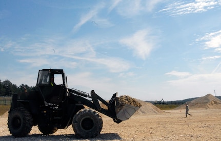 A Soldier with the 827th Engineer Company uses a front end loader to transport gravel to deposit at the site of a helicopter landing zone currently undergoing construction at the Joint Multinational Readiness Center in Hohenfels, Germany, Aug. 15, 2012. Soldiers with the 827th and 152nd Engineer Companies traveled to Hohenfels to aid in troop construction projects on the base's pre-deployment training area.