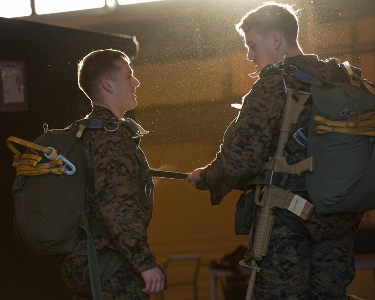 Marines with the 3rd Reconnaissance Battalion, 3rd Marine Division, III Marine Expeditionary Force, fasten and check a parachute at Yokota Air Base, Japan, Nov. 21, 2013. The training not only allowed the marines to practice jumping, but it also allowed the Yokota aircrews to practice flight tactics and timed-package drops. (U.S. Air Force photo by Osakabe Yasuo/Released)