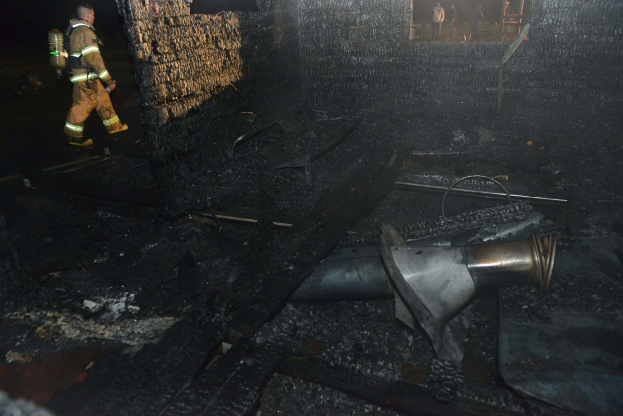 A JBER firefighter walks past the door of a cabin that burned Sept. 3 near Otter Lake. JBER Airmen rescued the family who was inside sleeping when the fire broke out. (U.S. Air Force photo/Airman 1st Class Ty-Rico Lea)