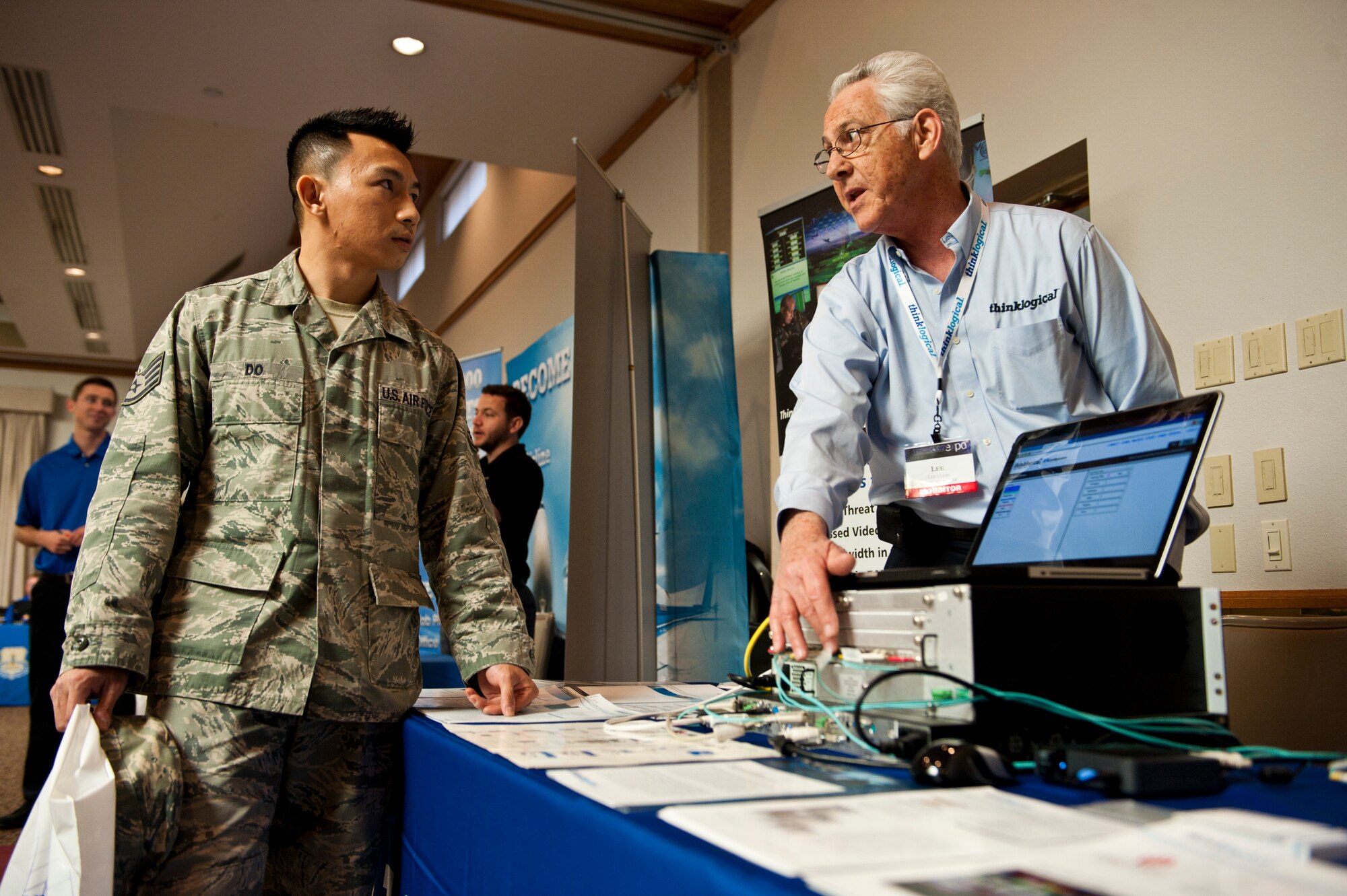 Lee Clem, thinklogical director of sales for the western region, discusses a product with Staff Sgt. Henry Do, 99th Communication Squadron client systems specialist, during the tech expo Nov. 21, 2013, at the Club at Nellis Air Force Base, Nev. Various technology companies came to Nellis AFB to advertise their products to interested units on base. (U.S. Air Force photo by Airman 1st Class Thomas Spangler) 