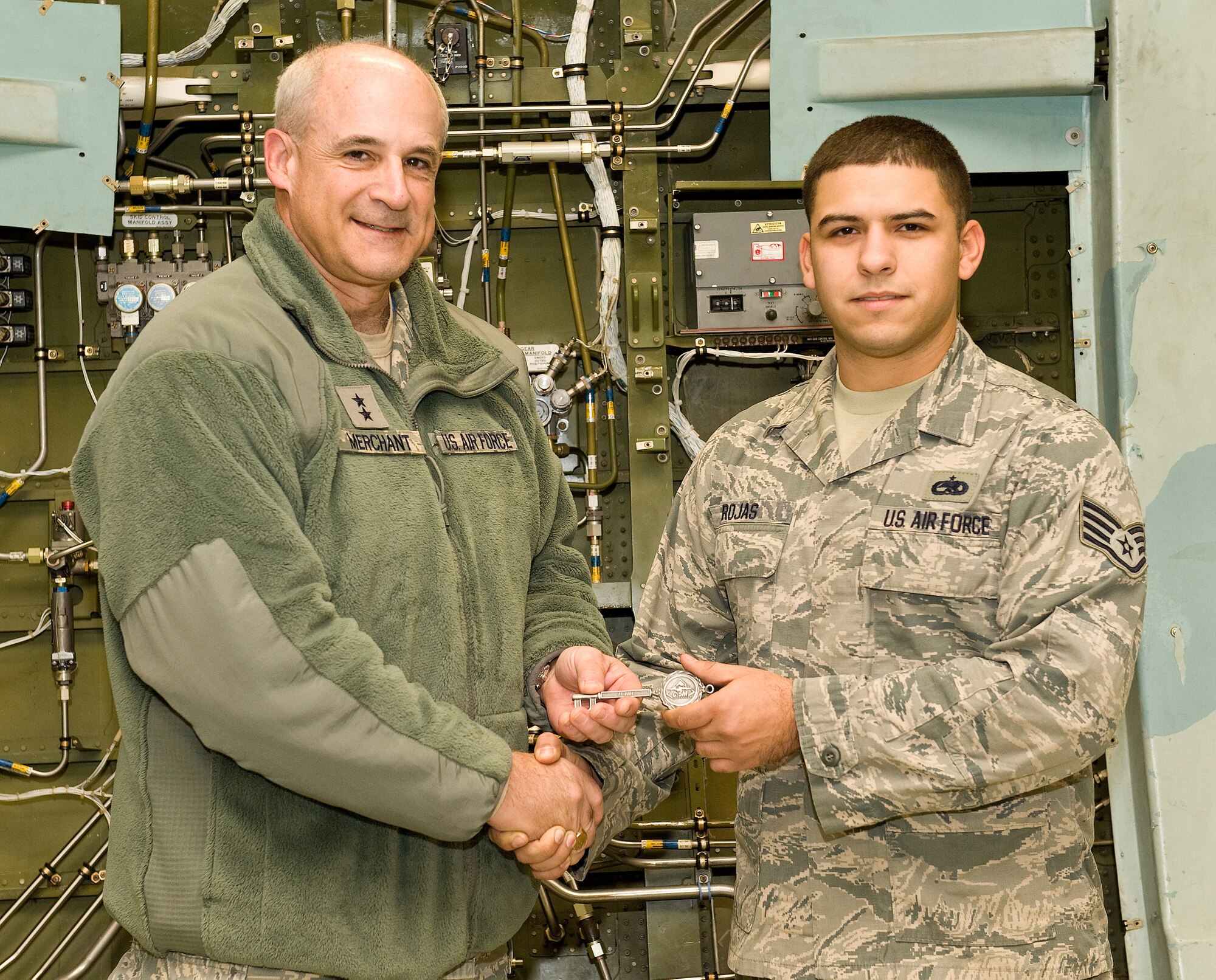 Maj. Gen. Kenneth D. Merchant, Director, Global Reach Programs, Office of the Assistant Secretary of the Air Force for Acquisition, Headquarters U.S. Air Force, Washington, D.C., left, presents Staff Sgt. Justin Rojas, 436th Aircraft Maintenance Squadron dedicated crew chief, right, the ceremonial aircraft key for Team Dover's newest C-5M Super Galaxy, 85-0004 Nov. 21, 2013, at Dover Air Force Base, Del. As dedicated crew chief, Rojas will be responsible for its maintenance, servicing and mission readiness. (U.S. Air Force photo/Roland Balik)