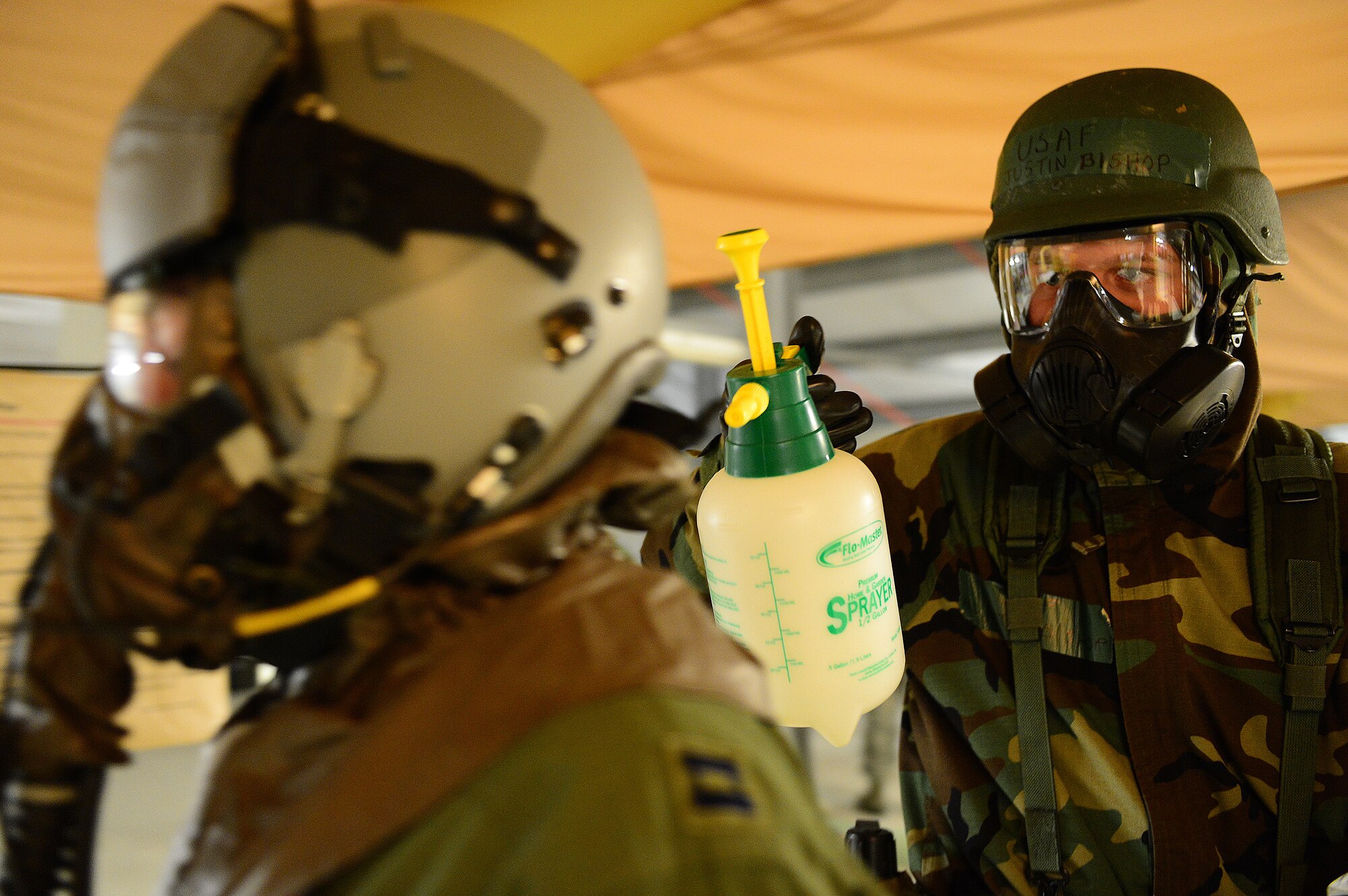 Airman 1st Class Justin Bishop, 48th Operations Support Squadron aircrew flight equipment apprentice, simulates spraying decontaminates on Capt. Brian Pascuzzi, 494th Fighter Squadron F-15E strike eagle pilot, during a Phase II exercise at Royal Air Force Lakenheath, England, Nov. 21, 2013. The exercise tested the 48th Fighter Wing’s readiness to support contingency operations. (U.S. Air Force photo by Airman 1st Class Dawn M. Weber/Released)