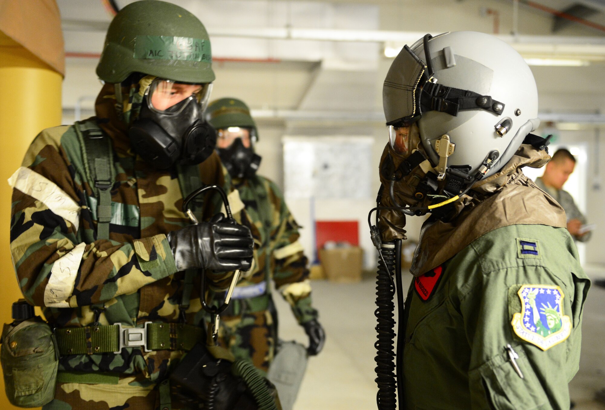 Airman 1st Class Justin Bishop, 48th Operations Support Squadron aircrew flight equipment apprentice, briefs Capt. Brian Pascuzzi, 494th Fighter Squadron F-15E strike eagle pilot, before decontamination procedures during a Phase II exercise at Royal Air Force Lakenheath, England, Nov. 21, 2013. The exercise tested the 48th Fighter Wing’s readiness to support contingency operations. (U.S. Air Force photo by Airman 1st Class Dawn M. Weber/Released)
