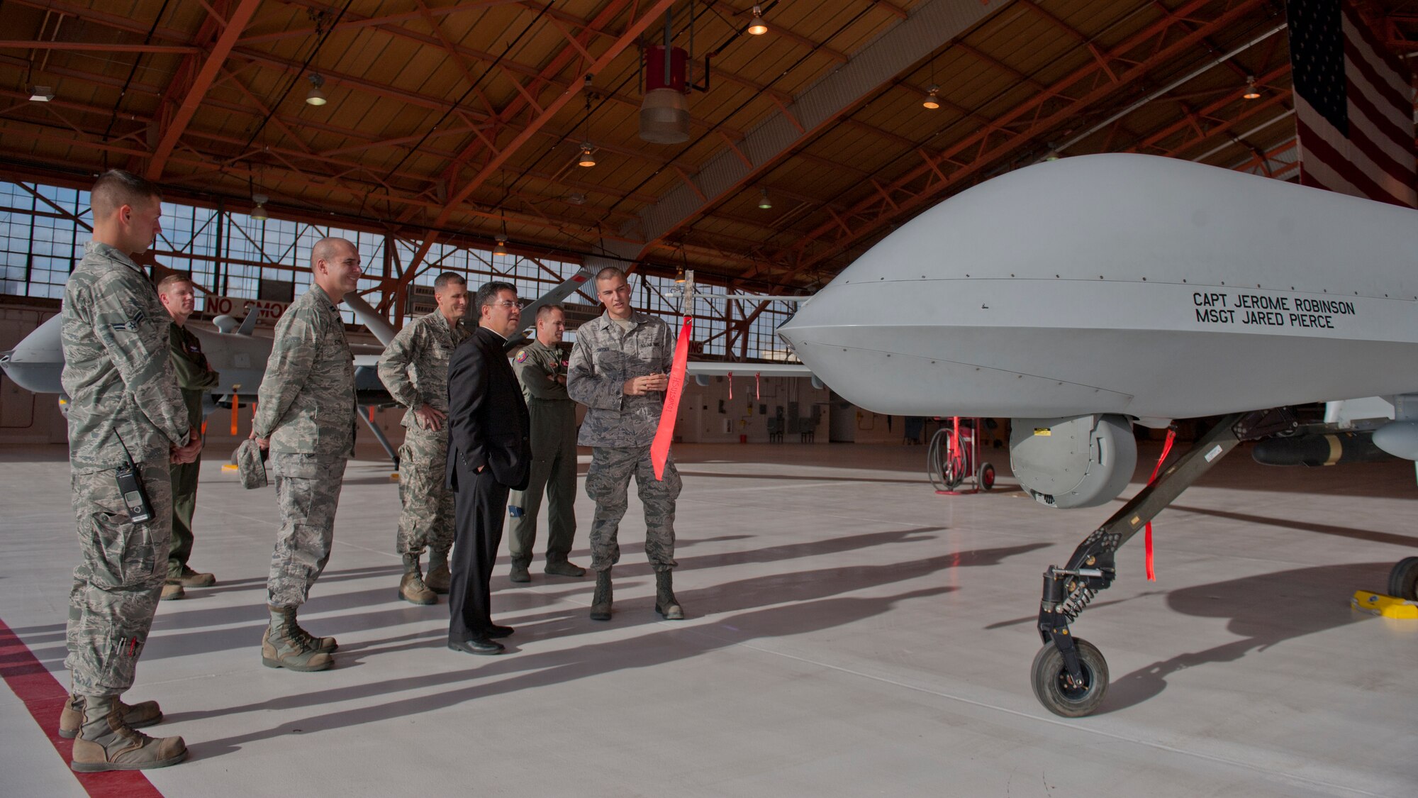 Senior Airman Timothy Snyder, 849th Aircraft Maintenance Squadron, describes the uses and abilities of the MQ-1 Predator and the MQ-9 Reaper to Bishop Oscar Cantu at Holloman Air Force Base, N.M., Nov. 20. Bishop Oscar Cantu has been appointed bishop-designate of the Roman Catholic Diocese of Las Cruces, in Las Cruces, N.M., by Pope Benedict XVI. Cantu was invited to Holloman to hold Catholic mass and to gain insight on the military lifestyle. (U.S. Air Force photo by Airman 1st Class Aaron Montoya/Released)