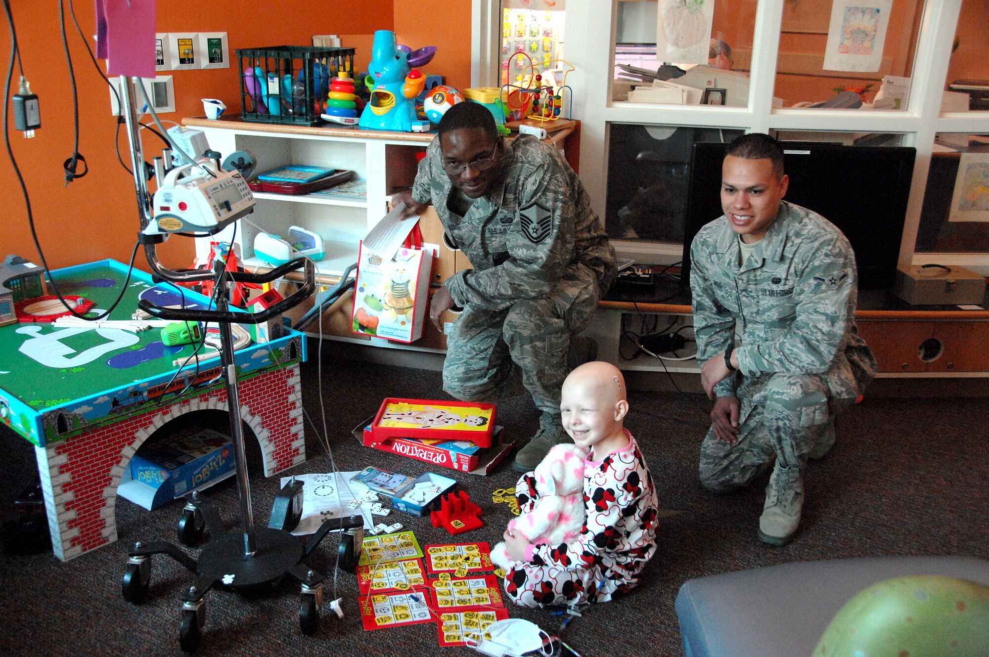 Master Sgt. Don Mitchell (left), 55th Force Support Squadron manpower analyst, and Airman Evan Rios, 55th Strategic Communications Squadron communications operator, who are both stationed at Offutt AFB, NE, pose for a photo with Lamya Luckey, 6, during a visit to Children’s Hospital & Medical Center in Omaha, NE, Nov. 20. They were part of a group of 12 volunteers who delivered over 90 stuffed animals on behalf of the Air Force Sergeants Association, Chapter 984. The special Noah’s Ark Workshop animals included 64 monkeys, puppy dogs, bears and cows that were assembled by Offutt members. These animals included an internal pouch where patients could place a star after making a wish. All of the animals were made available through donations to Chapter 984 of the AFSA. (U.S. Air Force photo by Delanie Stafford/Released)
