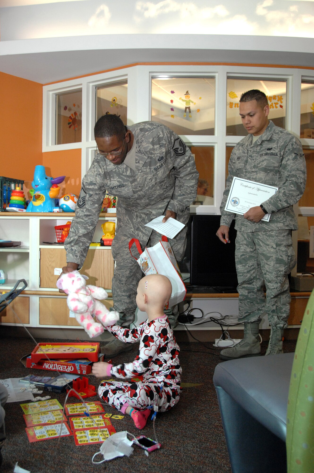 Master Sgt. Don Mitchell (left), 55th Force Support Squadron manpower analyst, and Airman Evan Rios, 55th Strategic Communications Squadron communications operator, Offutt AFB, NE, meet Lamya Luckey, 6, during a visit to Children’s Hospital & Medical Center in Omaha, NE, Nov. 20. They were part of a group of 12 volunteers who delivered over 90 stuffed animals on behalf of the Air Force Sergeants Association, Chapter 984. The special Noah’s Ark Workshop animals included 64 monkeys, puppy dogs, bears and cows that were assembled by Offutt members. These animals included an internal pouch where patients could place a star after making a wish. All of the animals were made available through donations to Chapter 984 of the AFSA. (U.S. Air Force photo by Delanie Stafford/Released)