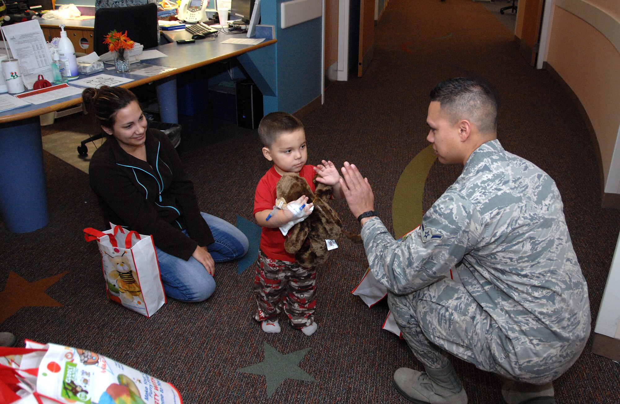 Airman Evan Rios, a Strategic Automated Command and Control System operator from the 55th Strategic Communications Squadron, Offutt AFB, NE, visits with Taylor Anderson, 2, during a visit to Children’s Hospital and Medical Center in Omaha, NE, Nov. 20. He was part of a group of 12 volunteers who delivered over 90 stuffed animals on behalf of the Air Force Sergeants Association, Chapter 984. The special Noah’s Ark Workshop animals included 64 monkeys, puppy dogs, bears and cows that were assembled by Offutt members. All of the animals were made available through donations to Chapter 984 of the AFSA. (U.S. Air Force photo by Delanie Stafford/Released)