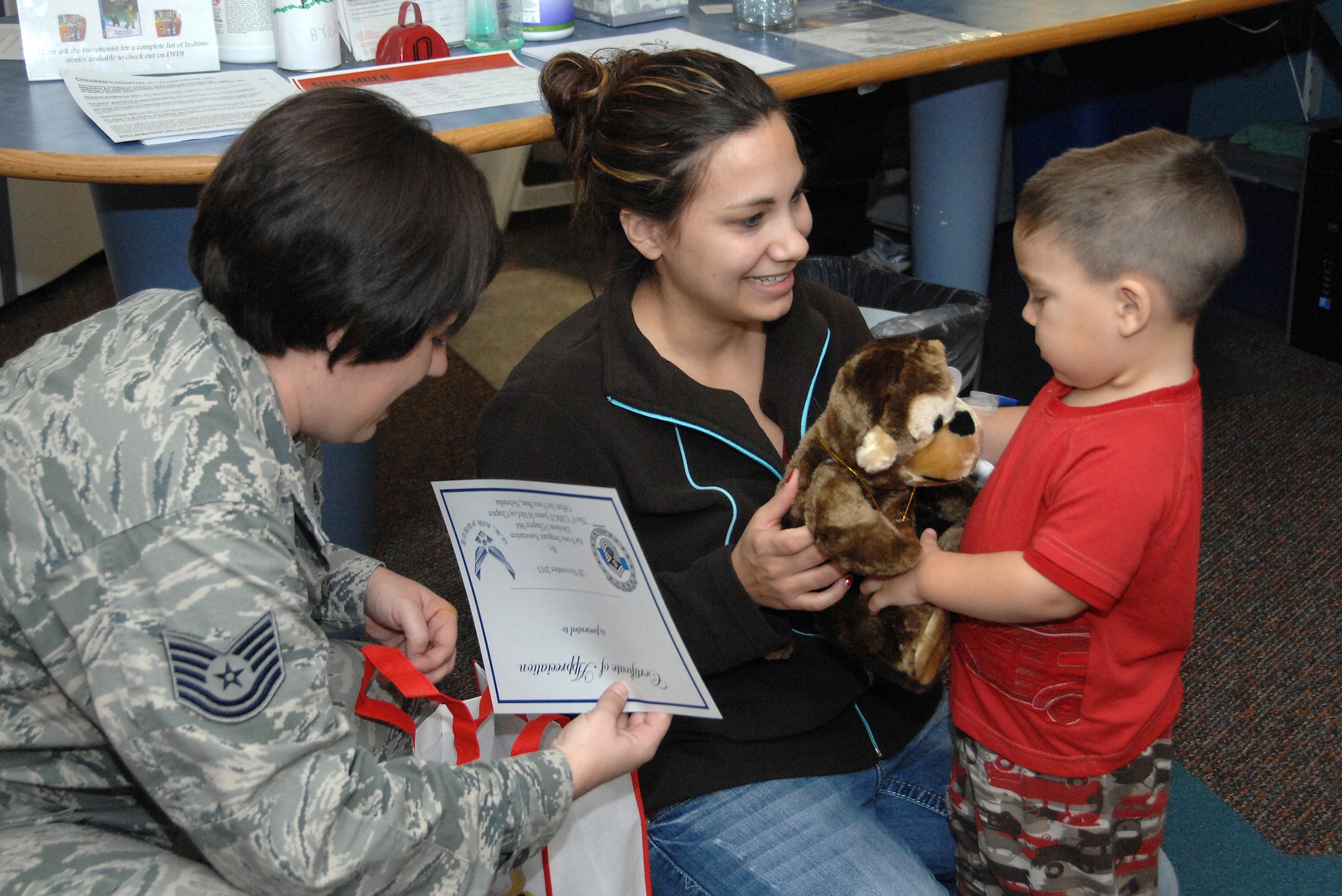 Tech. Sgt. Amanda Ramsey, a paramedic from the 1st ACCS, Offutt AFB , NE, presents a certificate of appreciation to Taylor Anderson, 2, during a visit to Children’s Hospital and Medical Center in Omaha, NE, Nov. 20. She was part of a group of 12 volunteers who delivered over 90 stuffed animals on behalf of the Air Force Sergeants Association, Chapter 984. The special Noah’s Ark Workshop animals included 64 monkeys, puppy dogs, bears and cows that were assembled by Offutt members. These animals included an internal pouch where patients could place a star after making a wish. All of the animals were made available through donations to Chapter 984 of the AFSA. (U.S. Air Force photo by Delanie Stafford/Released)