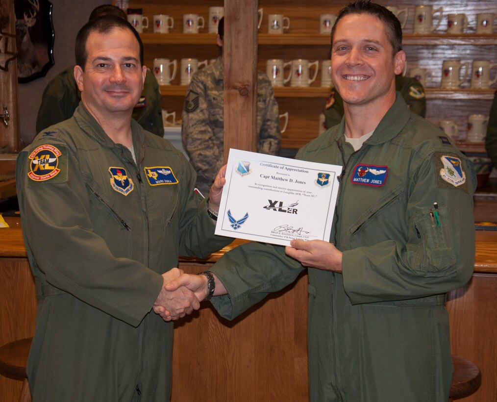 Capt. Mathew Jones, right, 87th Flying Training Squadron check flight commander, poses with Col. Mark Doria, left, 47th Flying Training Wing vice commander, after being presented the XLer of the week award here Nov. 20, 2013. The XLer is a weekly award chosen by wing leadership and given to those who consistently make outstanding contributions to Laughlin and their unit. (U.S. Air Force photo/Joel Langton)