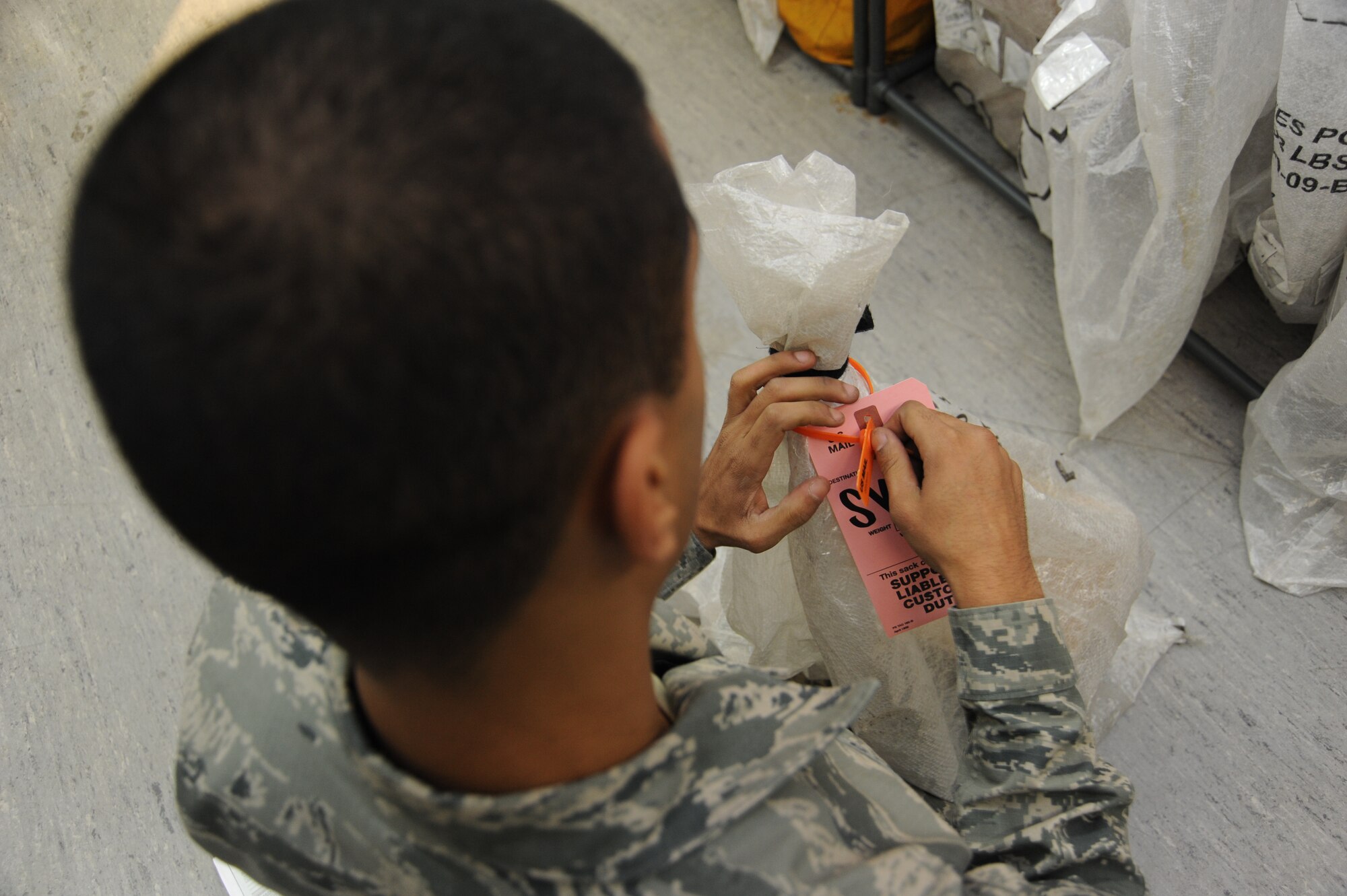 SPANGDAHLEM AIR BASE, Germany --- Senior Airman David Mota, a postal specialist with the 52nd Communications Squadron, ties a tag around a bag full of mail at the post office Nov. 20, 2013. Post office personnel advise Airmen wishing to send packages back to the continental United States to be mindful of pending deadlines for the holiday season.  (U.S. Air Force photo by Airman 1st Class Dylan Nuckolls/Released)