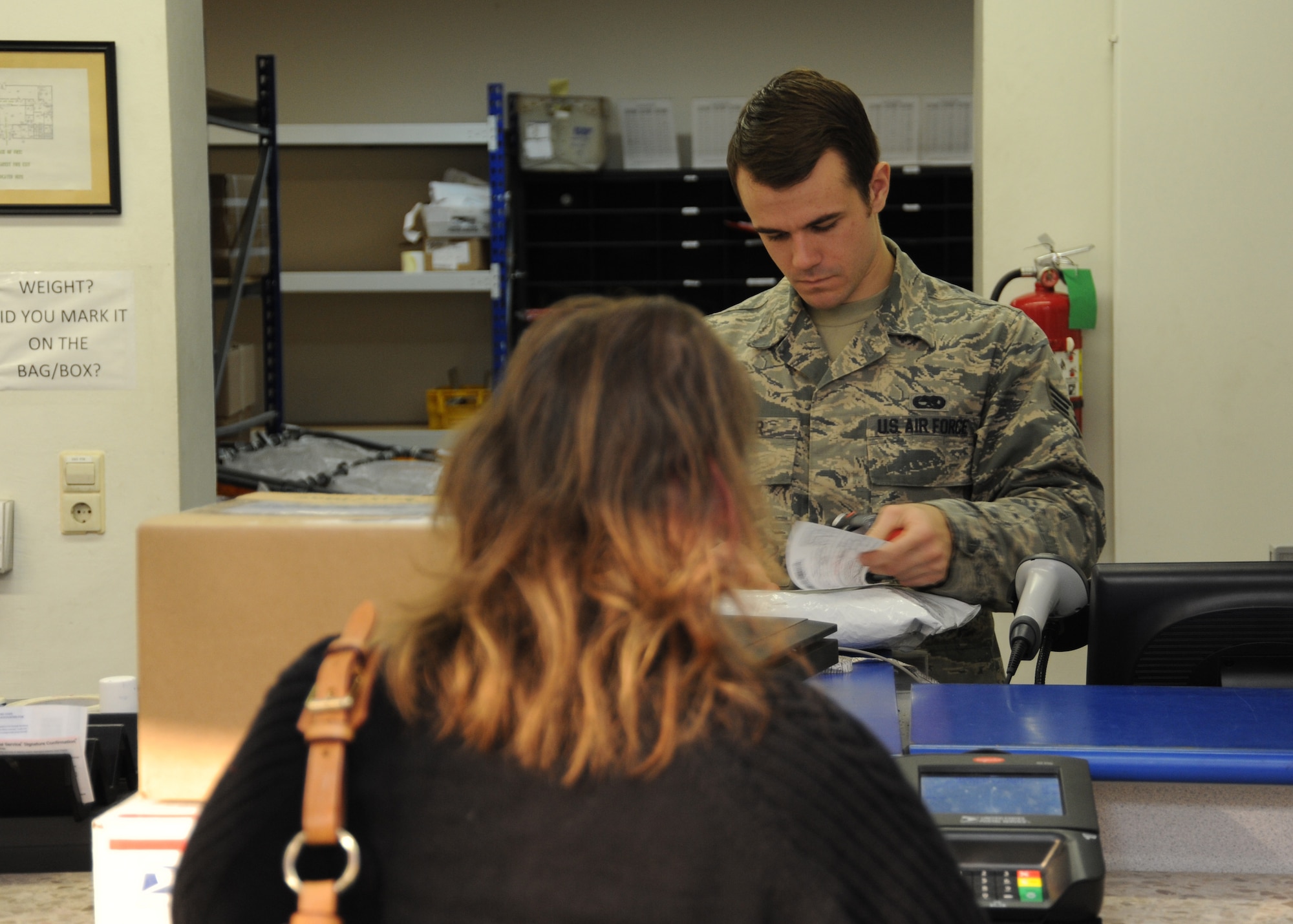 SPANGDAHLEM AIR BASE, Germany --- Senior Airman Matthew Baker, a postal customer service specialist with the 52nd Communications Squadron, accepts a package from a customer to ship at the post office Nov. 20, 2013. Postal service personnel suggest customers follow recommended standards for writing addresses and adhere to federal regulations against mailing unauthorized products. (U.S. Air Force photo by Airman 1st Class Dylan Nuckolls/Released)