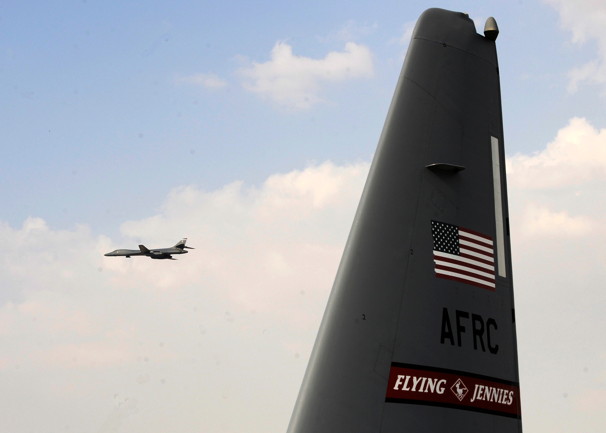 A B-1B Lancer flies past the tail of a C-130J Hercules during the 2013 Dubai Airshow at the Dubai World Central airport in Jebel Ali, United Arab Emirates, Nov. 20, 2013. The Lancer is assigned to the 9th Expeditionary Bomb Squadron deployed from Dyess Air Force Base, Texas. The United States participates in the Dubai Air Show to demonstrate a commitment to regional security, to demonstrate the flexibility of airpower, and to strengthen military-to-military relationships with regional partners.  (U.S. Air Force photo/Senior Airman Bahja J. Jones)