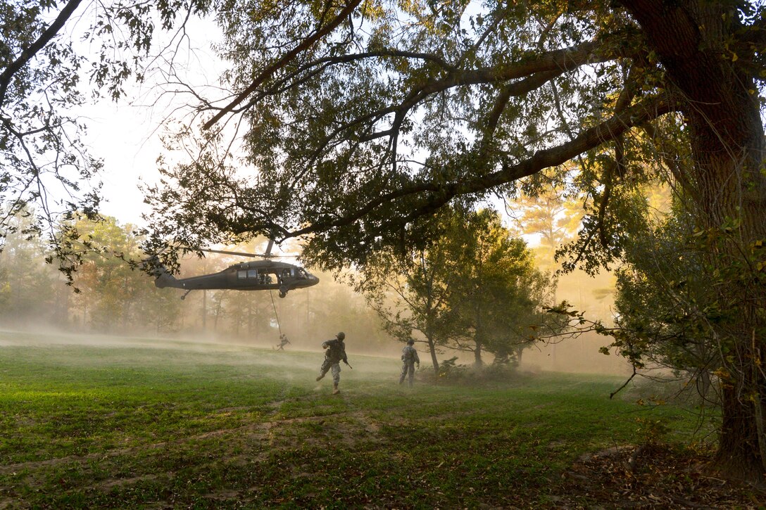 A soldier runs for the tree line, while another soldiers fast ropes from a UH-60 Black Hawk helicopter during phase two of Reconnaissance Surveillance Leaders Course on Fort Benning, Ga,, Nov. 11, 2013. 