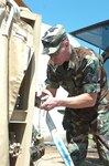 Technical Sgt. Brian Sutton, a utilities systems management specialist with the 188th Fighter Wing's Civil Engineering Squadron of the Arkansas Air National Guard, connects a supply hose to a water purification unit that will output purified water to support the water needs of the 1,230 residents of Dierks, Ark. The community's only water treatment facility was heavily damaged by a tornado on April 9, 2009.