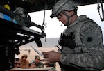 Sgt. 1st Class Aaron Christianson, Illinois Army National Guard's Headquarters and Headquarters Sustainment Brigade, 2nd Battalion, 122nd Field Artillery based in Chicago, reviews and fills prescriptions at Kuchi Village during their medical assistance visit April 5.