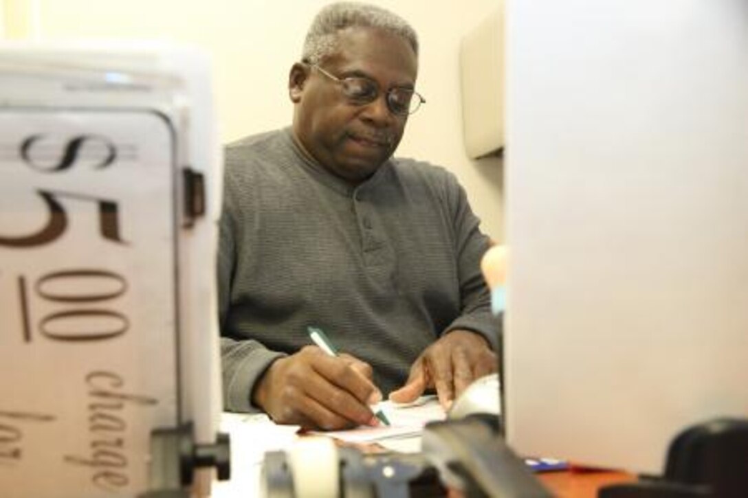 David L. Davis, facilities maintenance and services assistant on Marine Corps Logistics Base Barstow, Calif., reviews a work order at his desk, Nov. 20. Facilities maintenance works to keep buildings and equipment on MCLB Barstow in working order