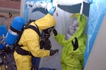 Sgt. 1st Class Ryan Van Damme, a decontamination noncommissioned officer for the 14th Civil Support Team of the Connecticut National Guard, checks Sgt. John Barton, a survey team member, for contaminates after Barton returned from surveying the inside of a local school in Groton, Conn., on May 5, 2009.