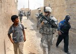 Spc. Adam Feldon, center, talks with an Iraqi boy, May 4, as a patrol of Pennsylvania Army National Guard Soldiers and Iraqi police officers moves through Taji market, north of Baghdad. The Keystone Guardsmen are from Company C, 1st Battalion, 112th Infantry Regiment, 56th Stryker Brigade Combat Team.