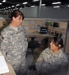 Army Sgt. 1st Class Angela Amundson, left, discusses correct wording for awards with one of her soldiers at Contingency Operating Base Basra, Iraq, May 6, 2009. The mother of two will spend Mother's Day helping other deployed mothers observe the day.