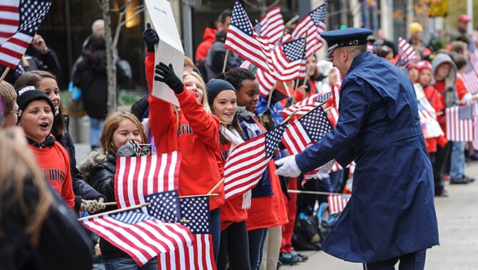 Second Lt. Justin Lewis greets on-lookers of a Veterans Day parade Nov. 11, 2013, in Pittsburgh, Penn. Lewis is a member of the Air Force Heritage of America Band. The band also performed at Heinz stadium in Pittsburgh for the Steelers vs. Bills NFL Salute to Service game Nov. 10, 2013. 
