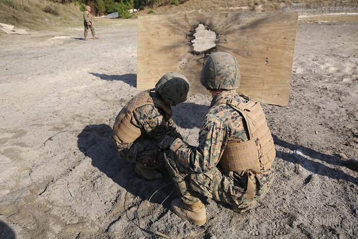 Marines with Improved Ribbon Bridge Platoon, 8th Engineer Support Battalion, 2nd Marine Logistics Group place an explosive charge, directed at a plywood board during a demolition training exercise aboard Camp Lejeune, N.C., Nov. 20, 2013. The platoon used explosives to puncture holes in doors and walls, clear concertina wire from a path and clear rooms of enemy combatants.