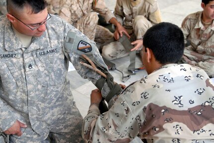 Louisiana Army National Guardsman Staff Sgt. Adam Sanchez of Pineville, La., has a member of the 11th Iraqi Army Engineer Regiment apply an improvised tourniquet during first aid training on May 13. Combat medics from the 225th Engineer Brigade of Pineville, La., taught members of the 11th Iraqi Army Engineer Regiment life-saving skills to include basic first aid, litter carry procedures, dressing a wound and how to apply a tourniquet.