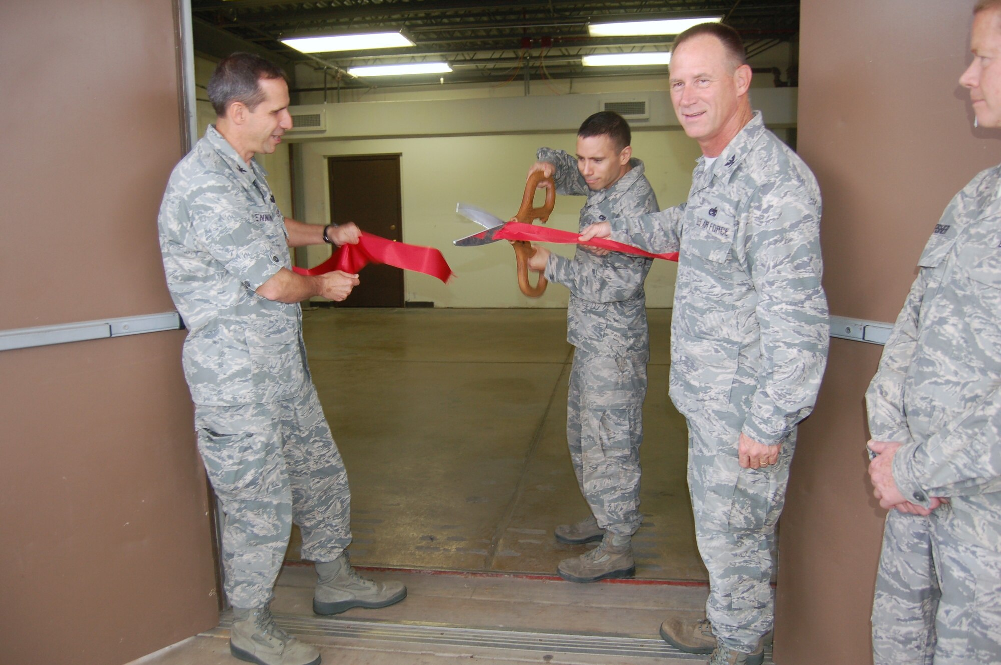 Col. Jeffrey Pennington, left, applauds the ribbon-cutting of the new Consolidated Tool Crib Nov. 21 as Col. Charles Combs, right, looks on.  The Crib opened for business after six months of renovation that included upgrading of heating and air-conditioning systems and replacement of all windows.