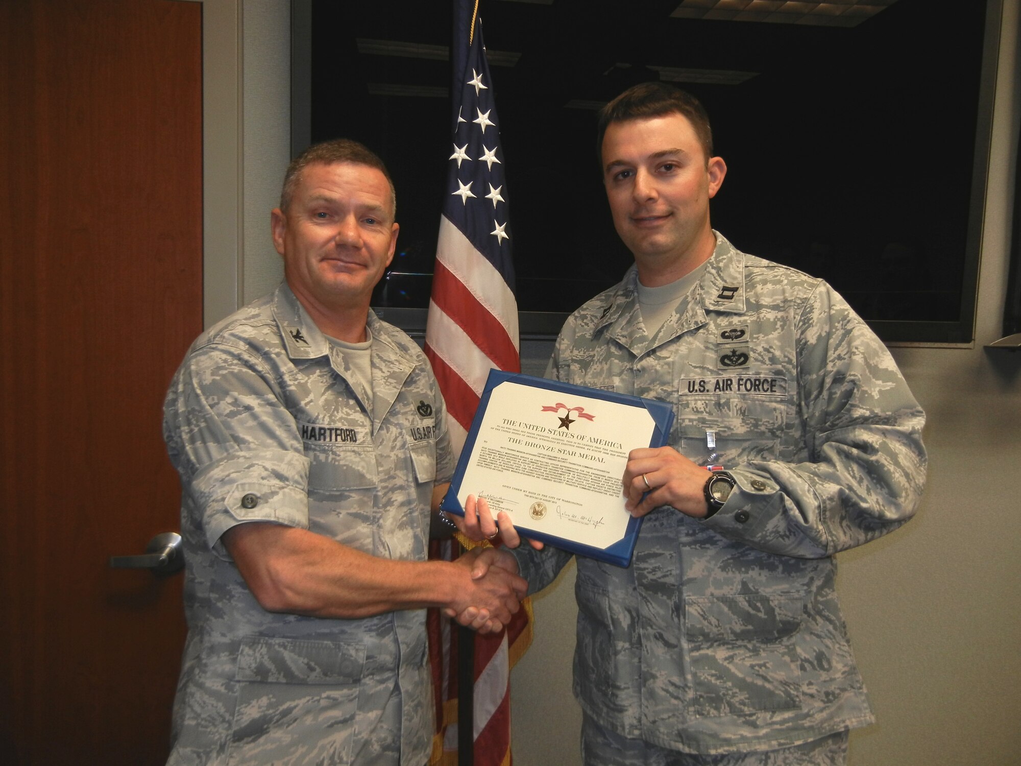 JOINT BASE SAN ANTONIO-LACKLAND, Texas -- Col. Scott Hartford, chief of the Air Force Civil Engineer Center’s Facility Engineering Directorate, presents Capt. Benjamin Knost with a Bronze Star Medal recently in recognition of his support of the Afghan Air Force Pilot Training Center at Shindand Air Base, Afghanistan. (U.S. Air Force photo/Jennifer Schneider)