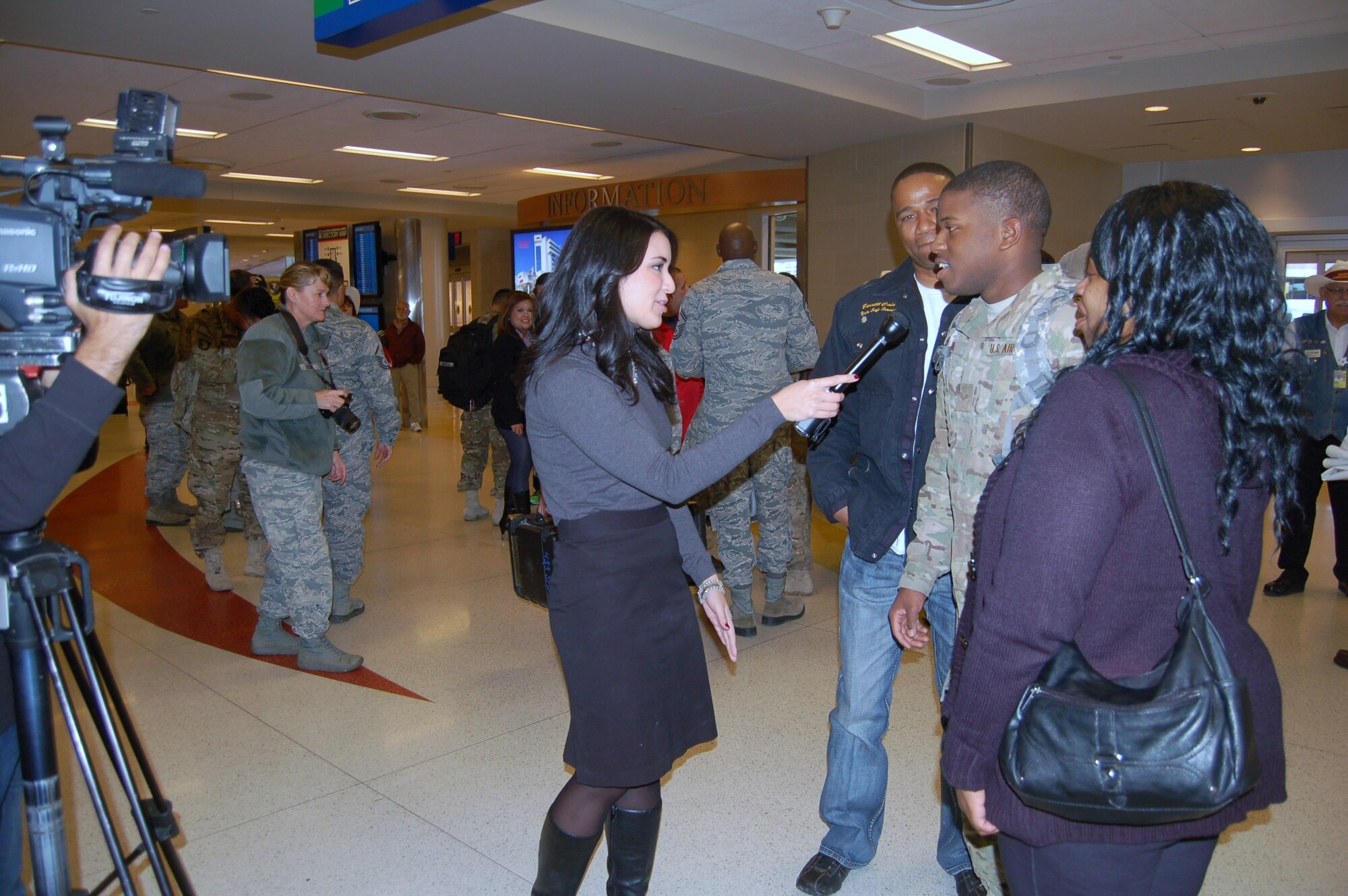 Senior Airman Barrett Cain III, 433rd Security Forces Squadron, is interviewed by Erin Nichols, a FOX 29 KABB-TV reporter at the San Antonio International Airport Nov. 22, 2013 upon returning from a six-month deployment to Bagram Air Base in Afghanistan.  Cain was one of 11 433rd SFS Airmen who returned home over a two-day period. Cols. Jeffrey Pennington, 433rd Airlift Wing commander, and Craig Petersen, 433rd Mission Support Group commander, were among the family members and wing personnel who greeted the returning Reservists.  