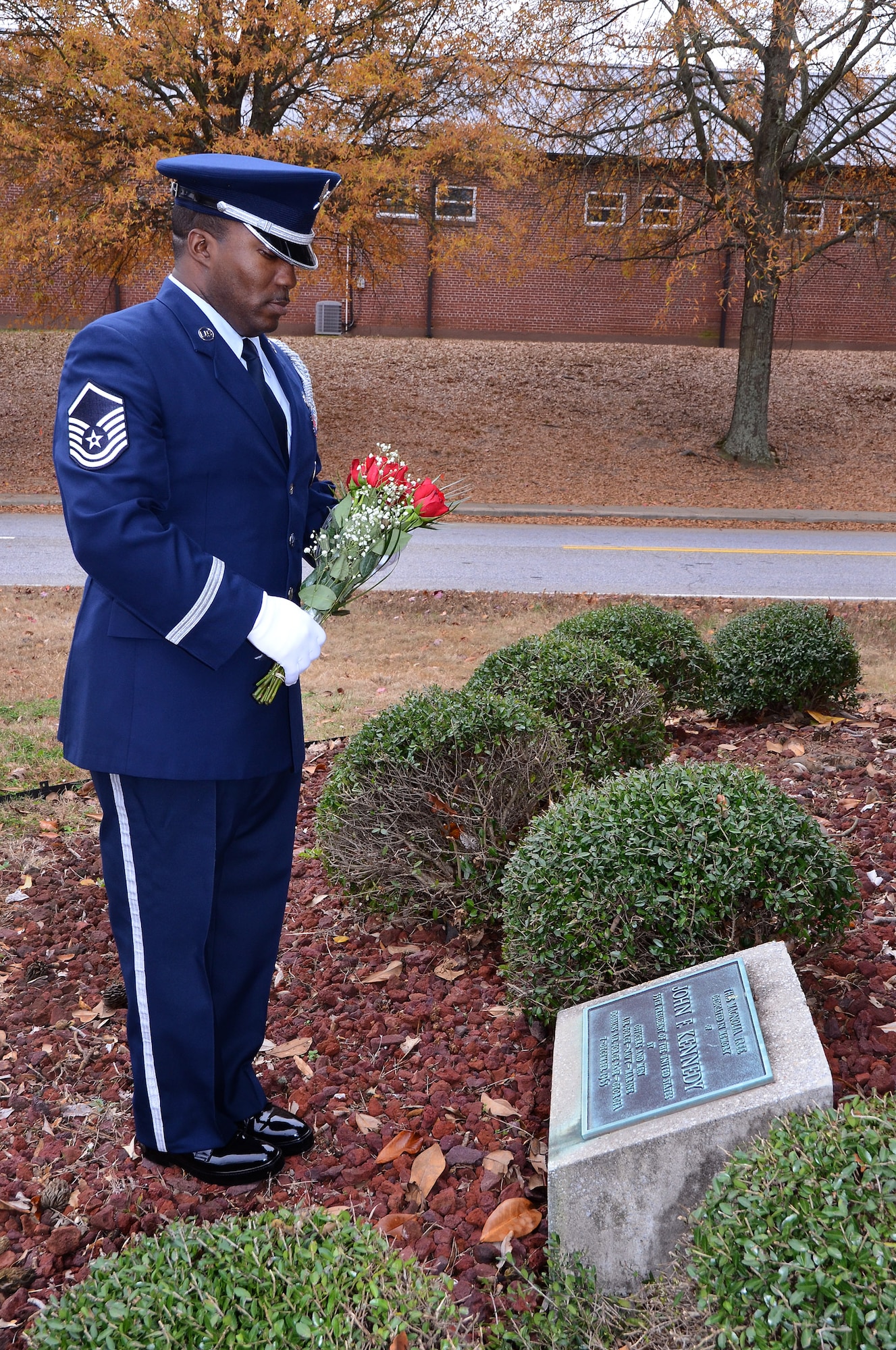 Master Sgt. Aaron Albright, 94th Airlift Wing Honor Guard superintendent, lays roses on a magnolia tree memorial on the 50th Anniversary of the assassination of John F. Kennedy, the 35th President of the United States Nov. 22 at Dobbins Air Reserve Base, Ga. Brig. Gen. George H. Wilson, Dobbins Air Force Base commander, ordered a tree be planted on base in memory of the President on Dec. 7, 1963. Members of Air Force Reserve units, the Marine Air Detachment, the Naval Air Station and the Georgia Air National Guard participated in the planting. (U.S. Air Force photo/Brad Fallin)