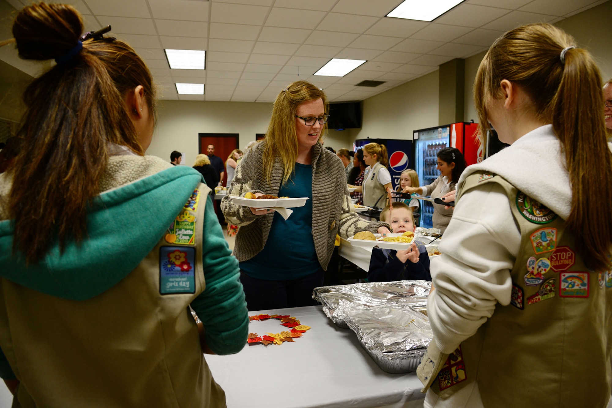 Members of the Girl Scouts of the Colonial Coast serve dinner to family members during the third annual “Thanks for Giving” potluck social at the 733rd Mission Support Group headquarters at Fort Eustis, Va., Nov. 21, 2013. Families of fallen Service members, known as "Gold Star families,” traveled from across the Hampton Roads area to share personal dishes and offer support to each other. (U.S. Air Force photo by Staff Sgt. Ashley Hawkins/Released)