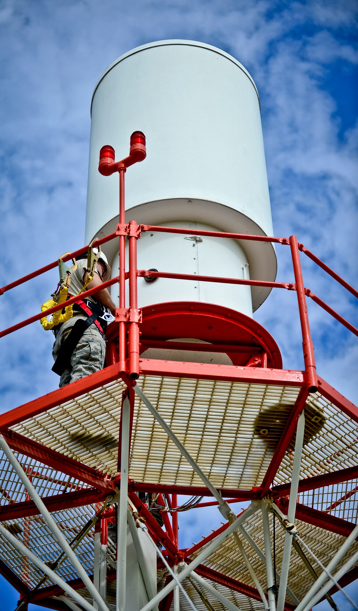 Senior Airman Brent Harmor, 6th Communications Squadron airfield systems technician, stands atop a tactical air navigation platform at MacDill Air Force Base, Fla., Nov. 5, 2013. Harmor climbed the tower in order to make repairs the lighting system and the structure containing the electrical equipment. (U.S. Air Force photo by Staff Sgt. Brandon Shapiro/Released)