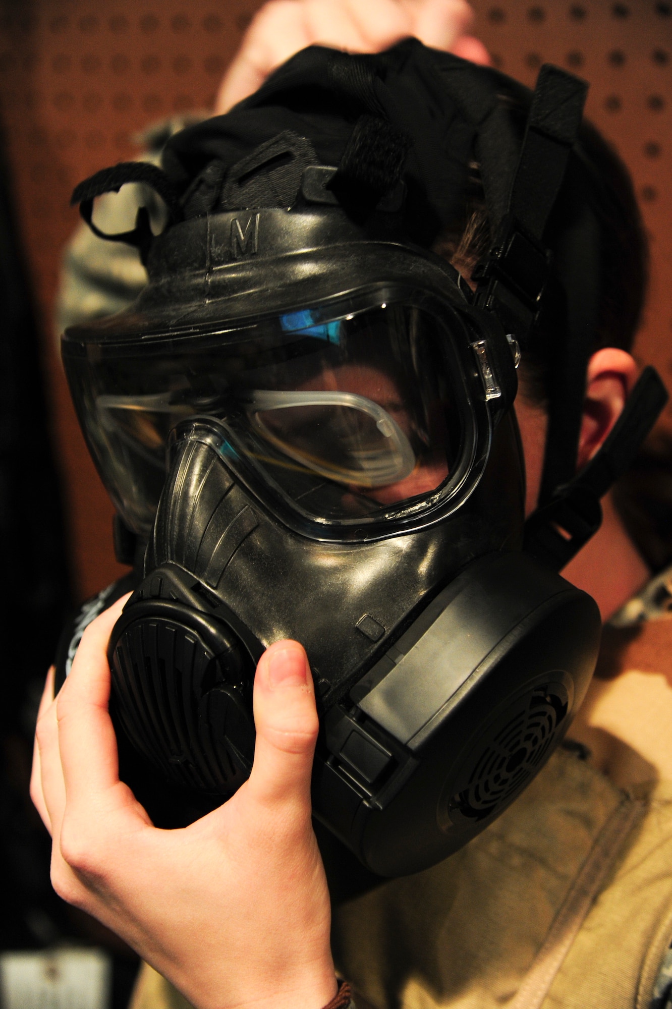ALTUS AIR FORCE BASE, Okla. -- U.S. Air Force Senior Airman Krystal Brittain, 97th Operations Support Squadron airfield management specialist, dons her gas mask during combat arms training Nov. 21, 2013. Airmen are required to wear protective equipment to include an Advanced Combat Helmet, tactical vest and gas mask during certain portions of the weapons qualification training.  (U.S. Air Force Photo by Senior Airman Lausanne Genuino/Released)
